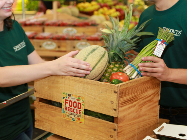 Sprouts employees pack food into a wooden crate