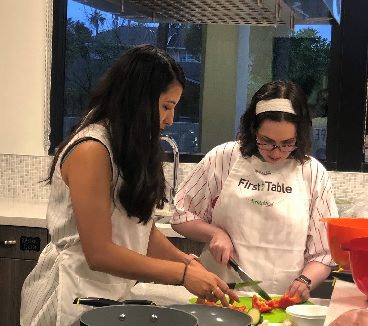 Two women prepare vegetables in a kitchen.