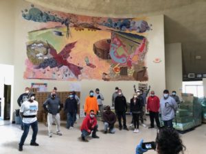 volunteers unloading donated food in a room with a mural