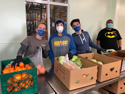 Volunteers pack bags of groceries and produce for emergency food distribution.
