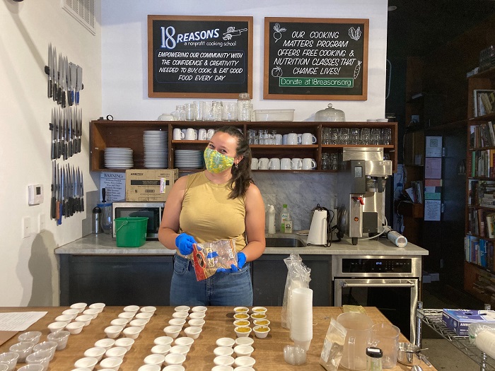 Young woman wearing a mask prepares small packages of food to donate.