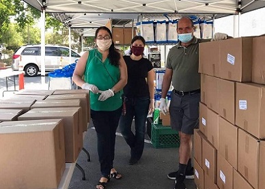 Volunteers hand out boxes of food at a distribution site.