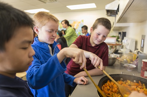 Boys stir sweet potatoes for their recipe.