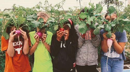 Kids hiding behind root vegetables.