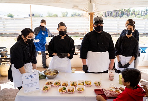 Young chefs stand together while waiting for feedback from the student judge.