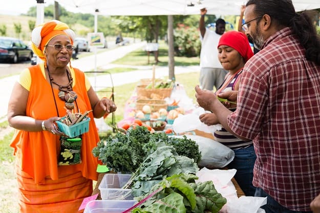 A woman purchases produce from a farm stand.