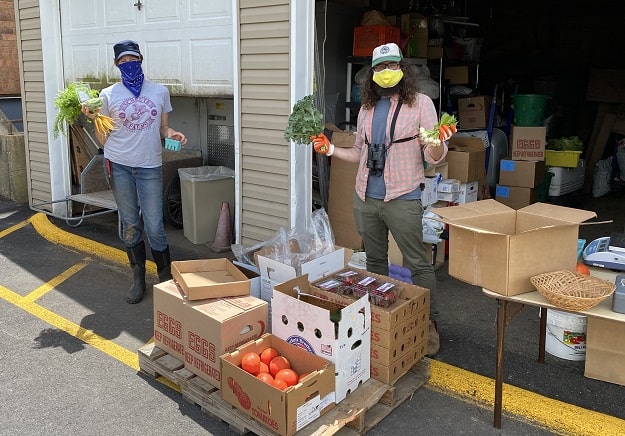 Two women stand holding produce during a food distribution.