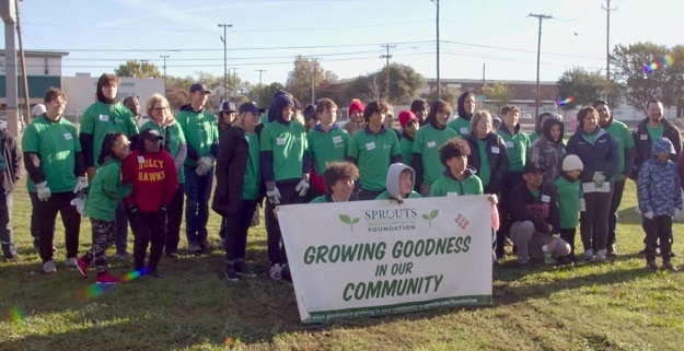 Volunteers in green tshirts smile for a group photo.
