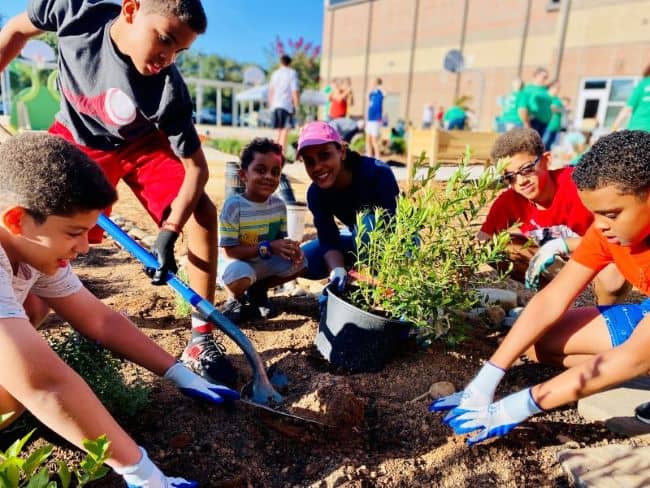 Students and parents smile and work together in the school garden.